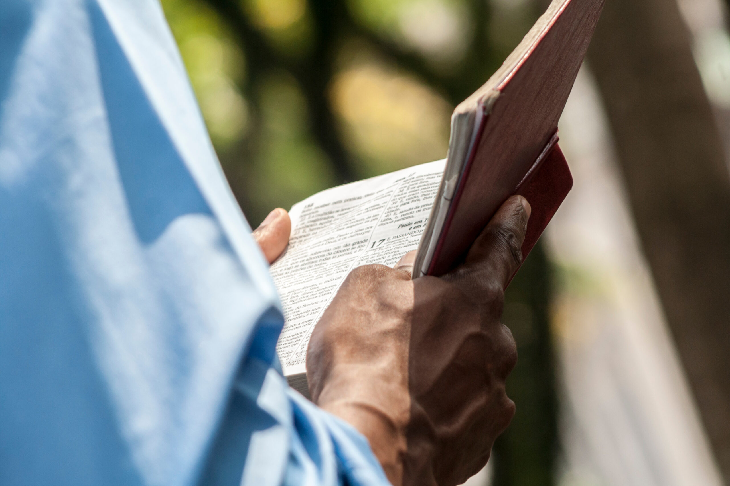 A community member holds a book outdoors.